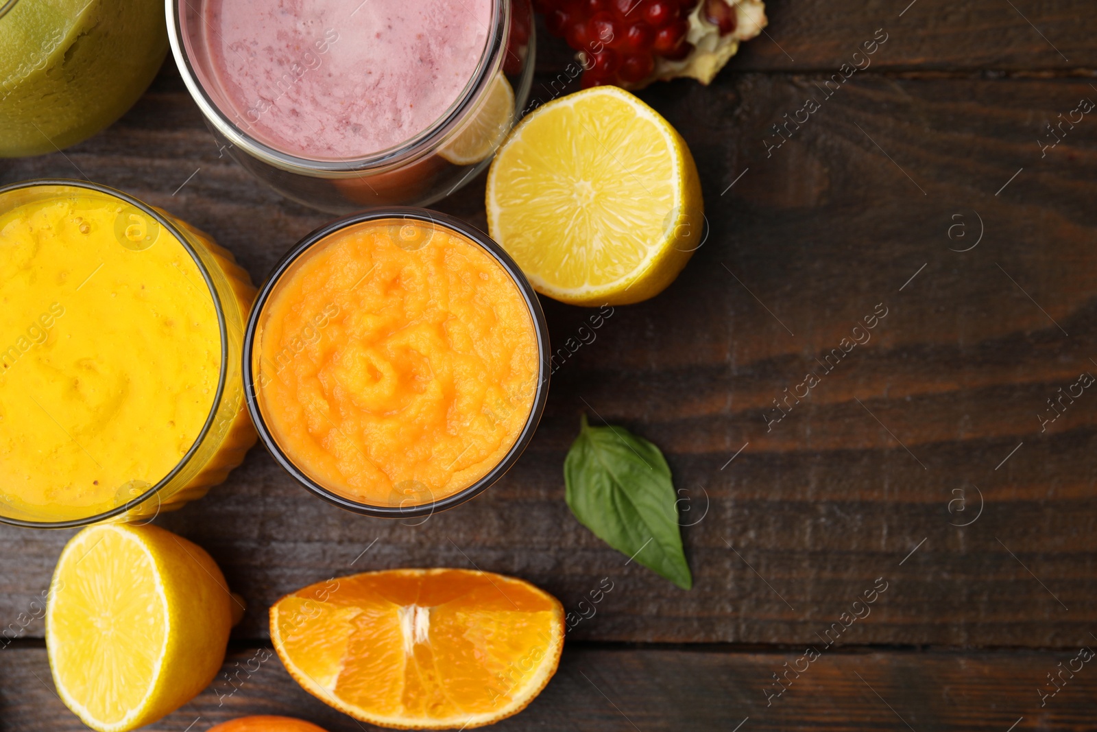 Photo of Tasty smoothies in glasses and ingredients on wooden table, flat lay. Space for text