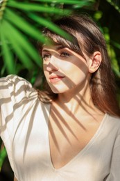 Portrait of beautiful woman in shadow of tropical leaf outdoors