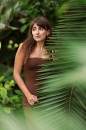 Portrait of beautiful woman near palm leaves outdoors