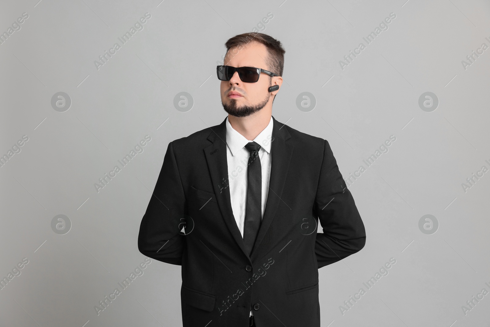 Photo of Young bodyguard in suit and sunglasses on grey background