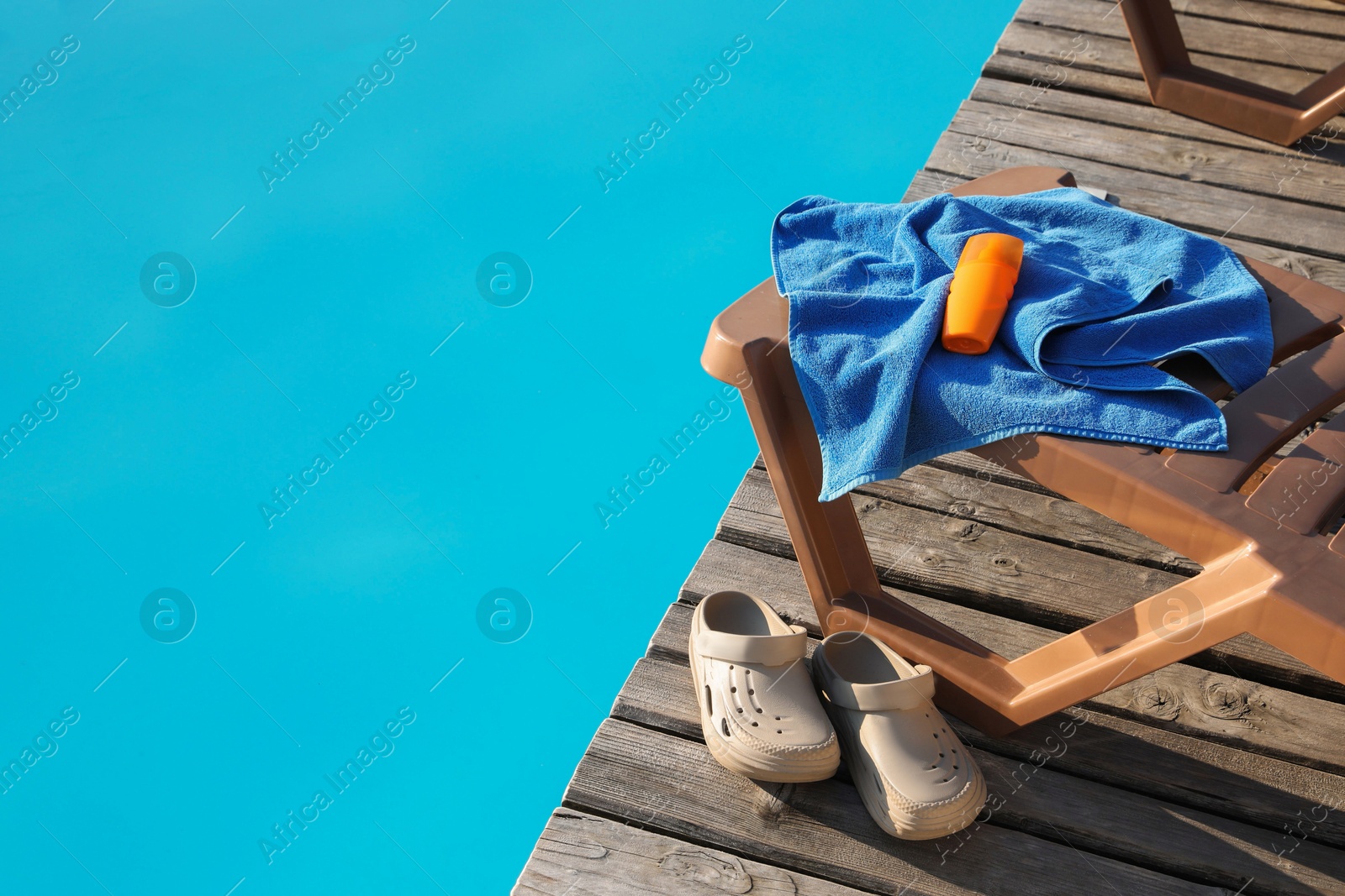 Photo of Beach accessories and sun loungers on wooden deck near outdoor swimming pool