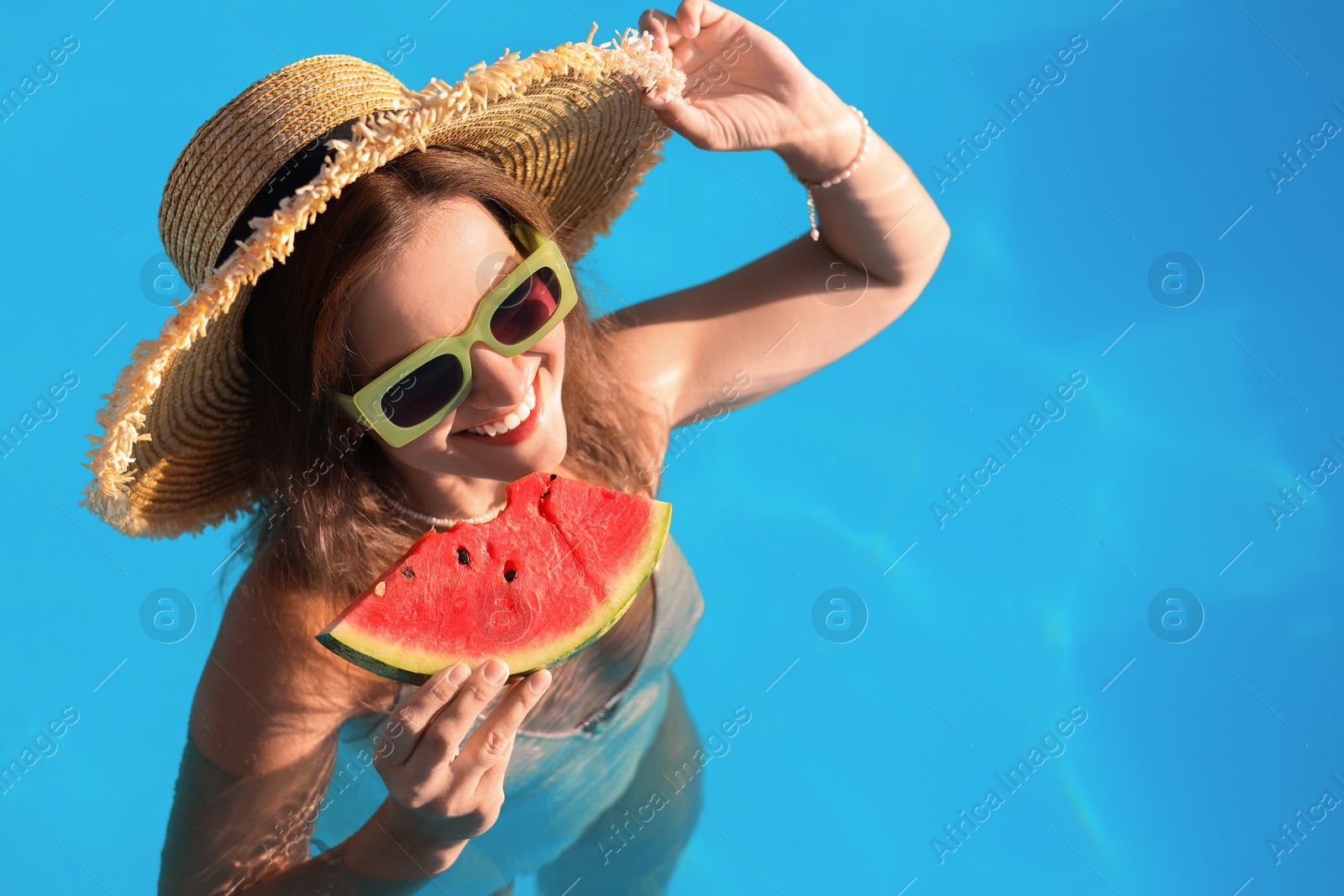 Photo of Happy woman with slice of juicy watermelon in swimming pool outdoors, space for text