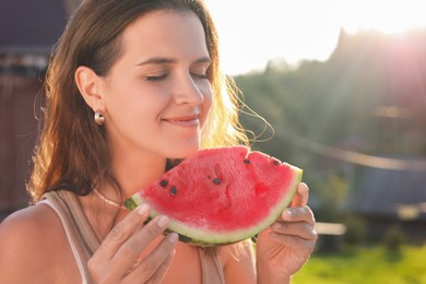 Happy woman with slice of juicy watermelon outdoors