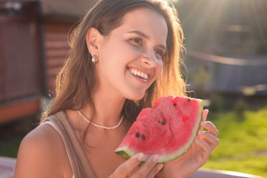 Happy woman with slice of juicy watermelon outdoors