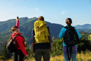 Friends with backpacks in beautiful mountains, back view