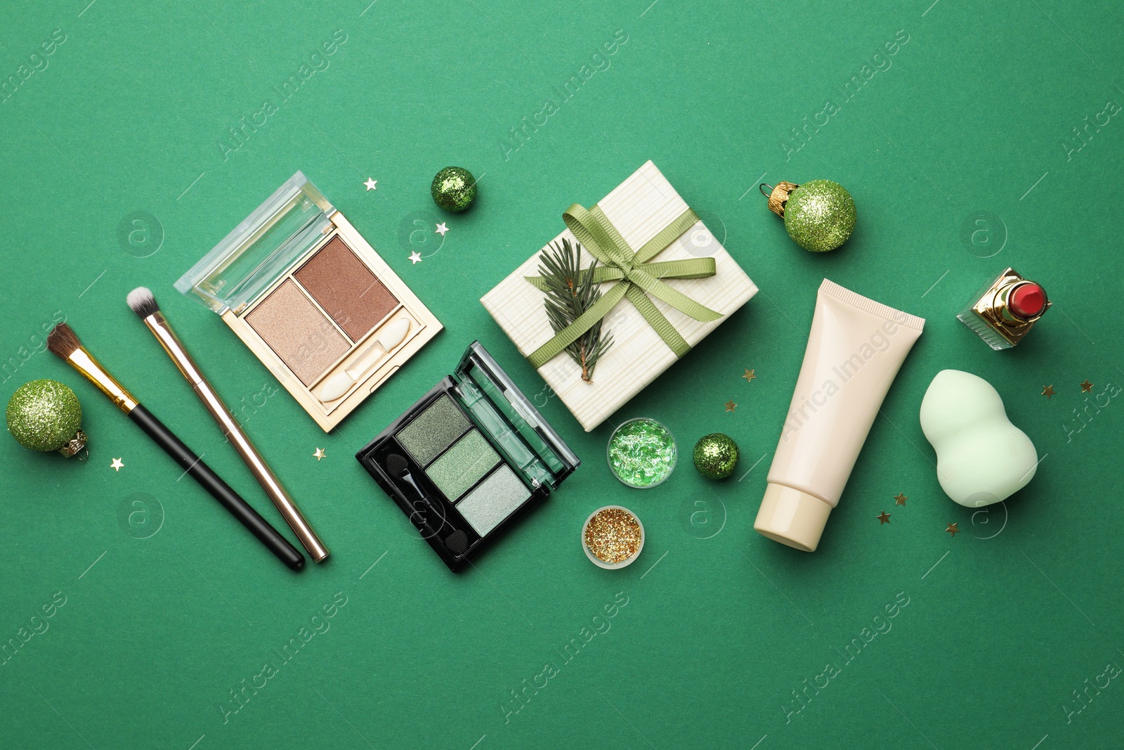 Photo of Flat lay composition with makeup products and Christmas decor on green background