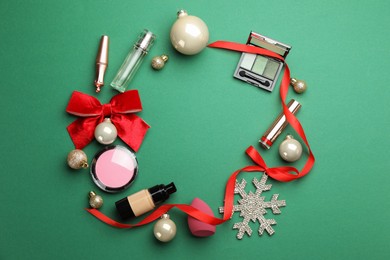 Photo of Frame made of makeup products and Christmas decor on green background, flat lay. Space for text