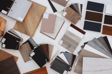 Photo of Different samples of wooden flooring on white table, top view