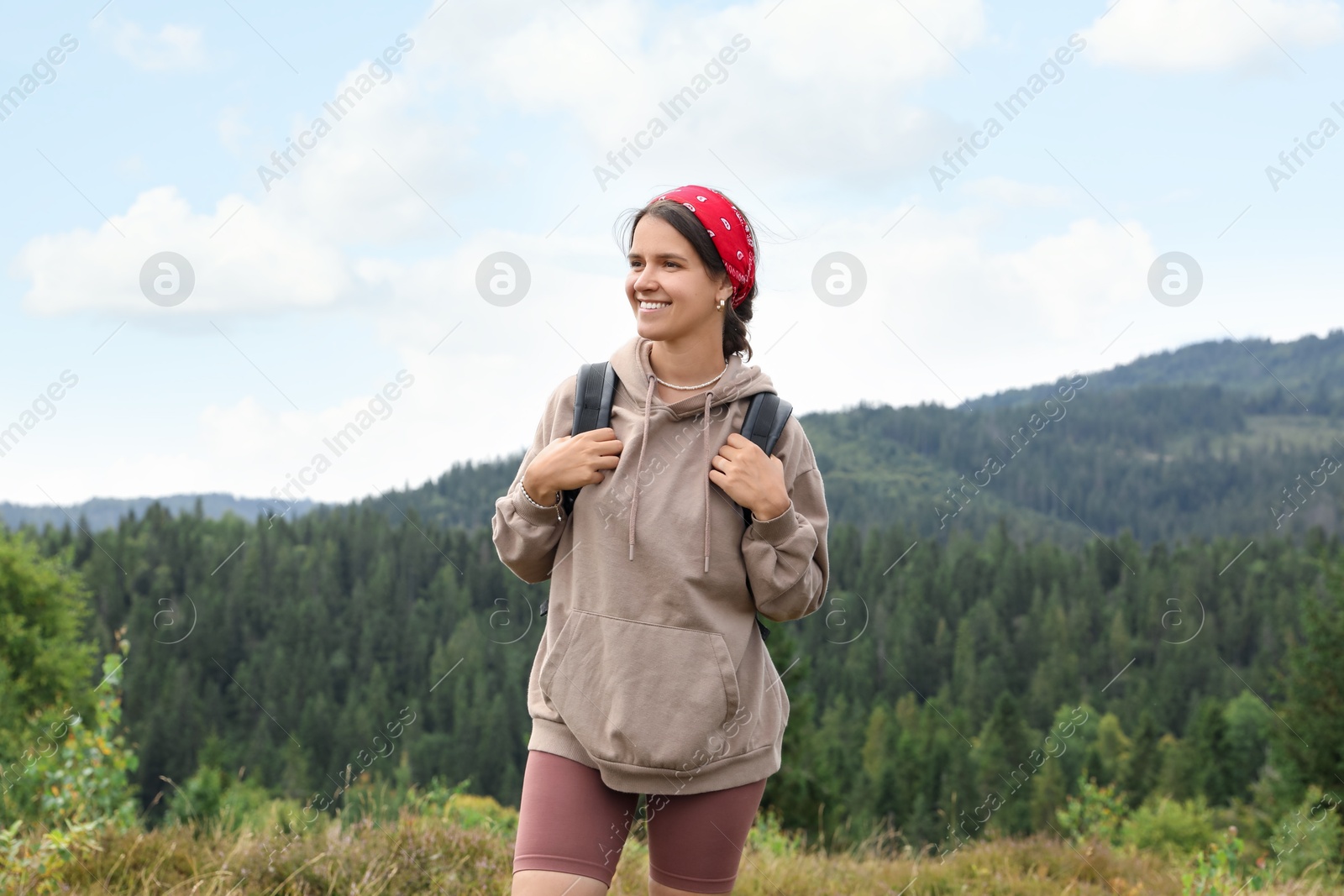 Photo of Smiling tourist with backpack walking in mountains