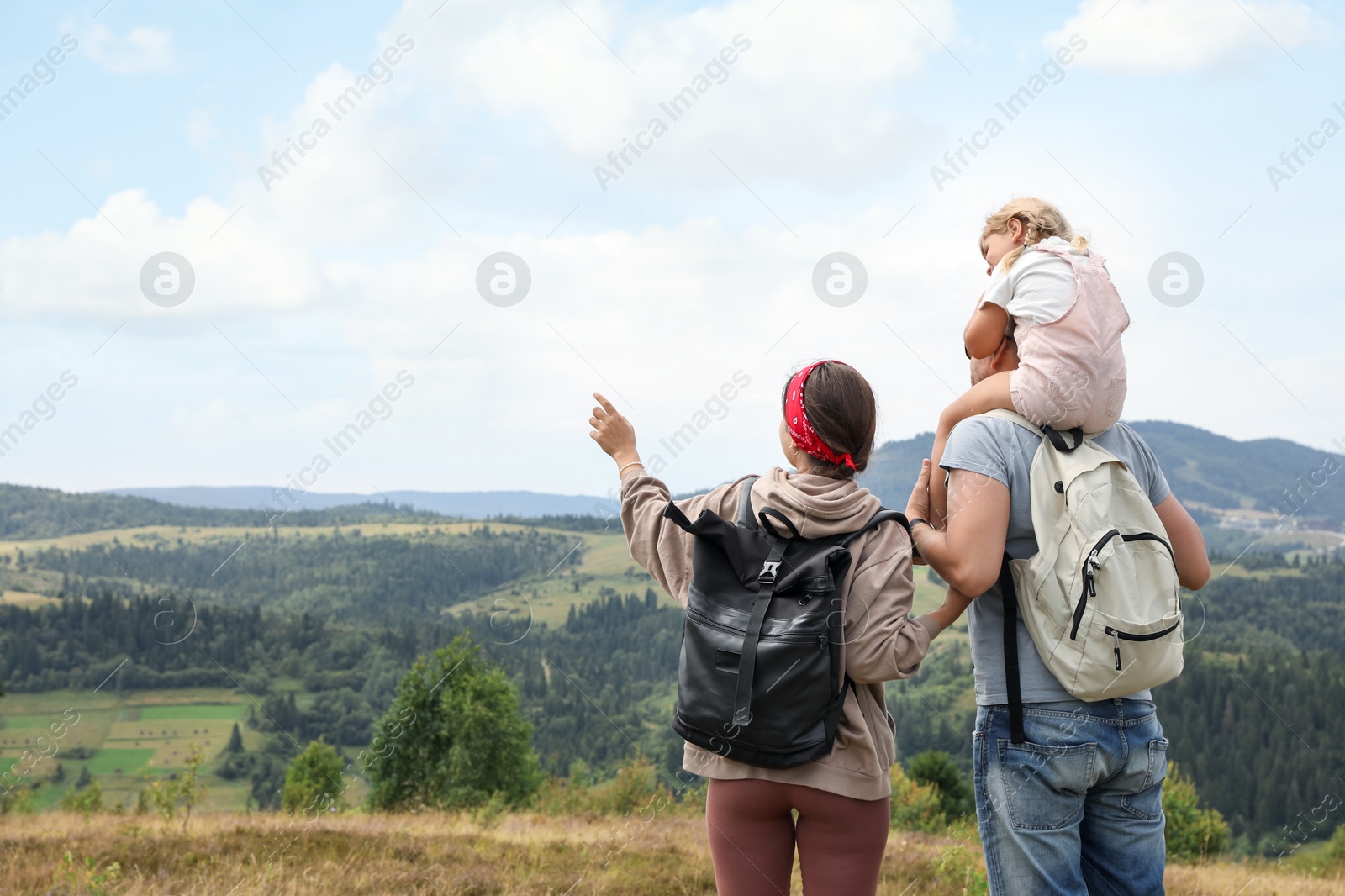 Photo of Family of tourists with backpacks enjoying picturesque landscape, back view. Space for text