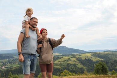 Happy family with backpacks travelling in mountains, space for text. Active tourism