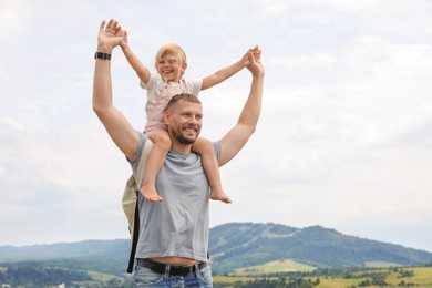 Happy tourist with his daughter and backpack travelling in mountains. Space for text