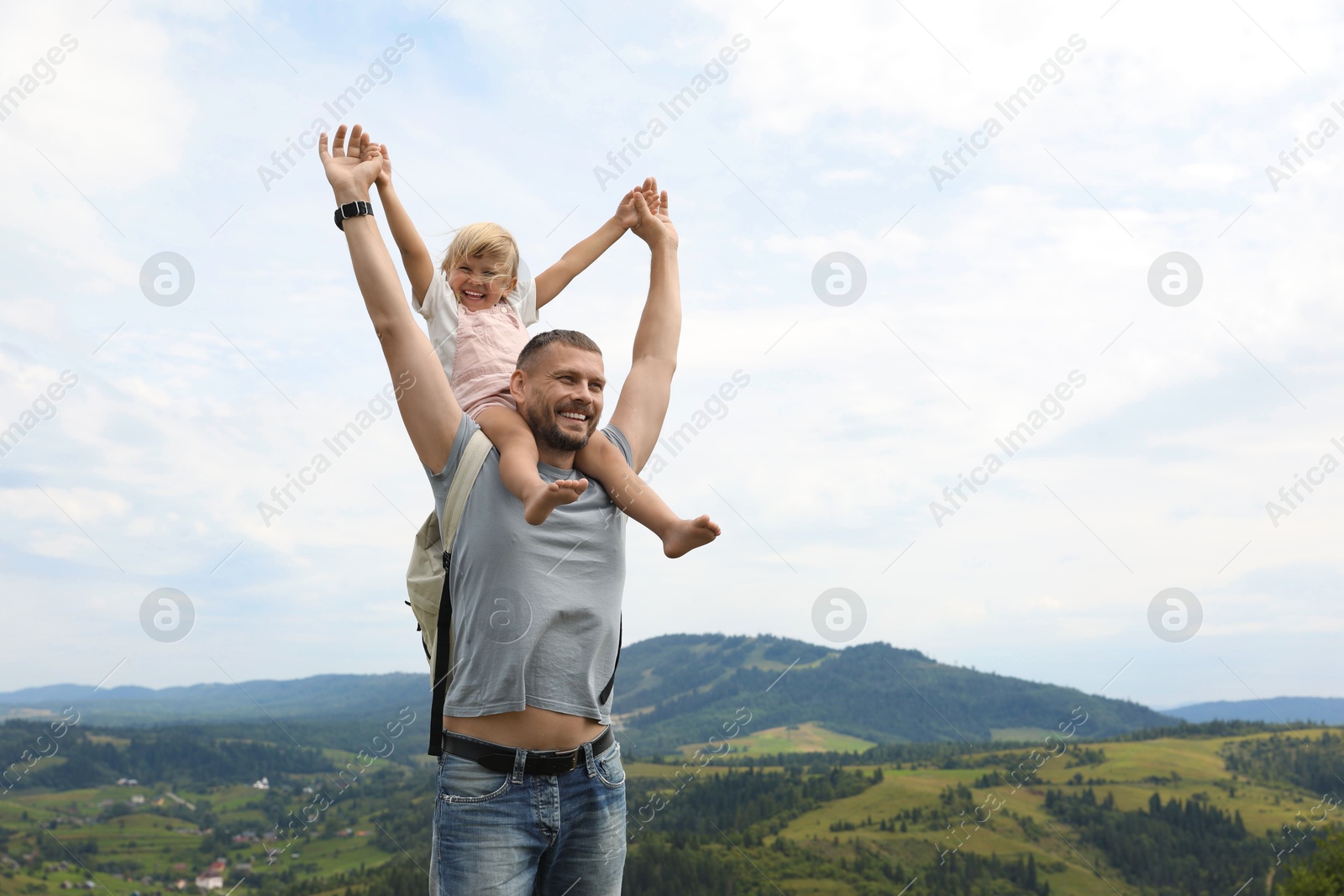 Photo of Happy tourist with his daughter and backpack travelling in mountains. Space for text