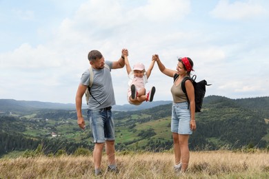 Photo of Happy family with backpacks travelling in mountains. Active tourism