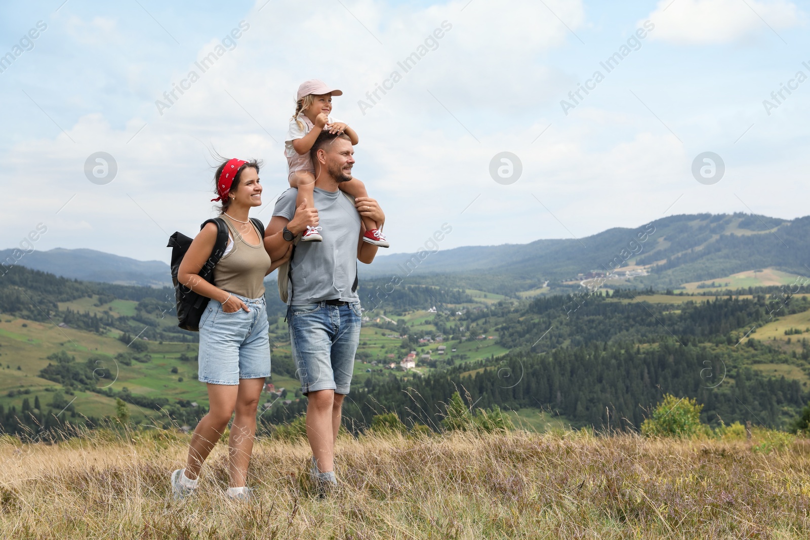 Photo of Happy family with backpacks travelling in mountains, space for text. Active tourism