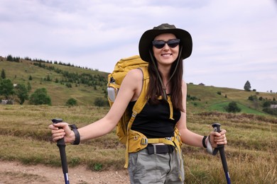 Young hiker with backpack and trekking poles in mountains