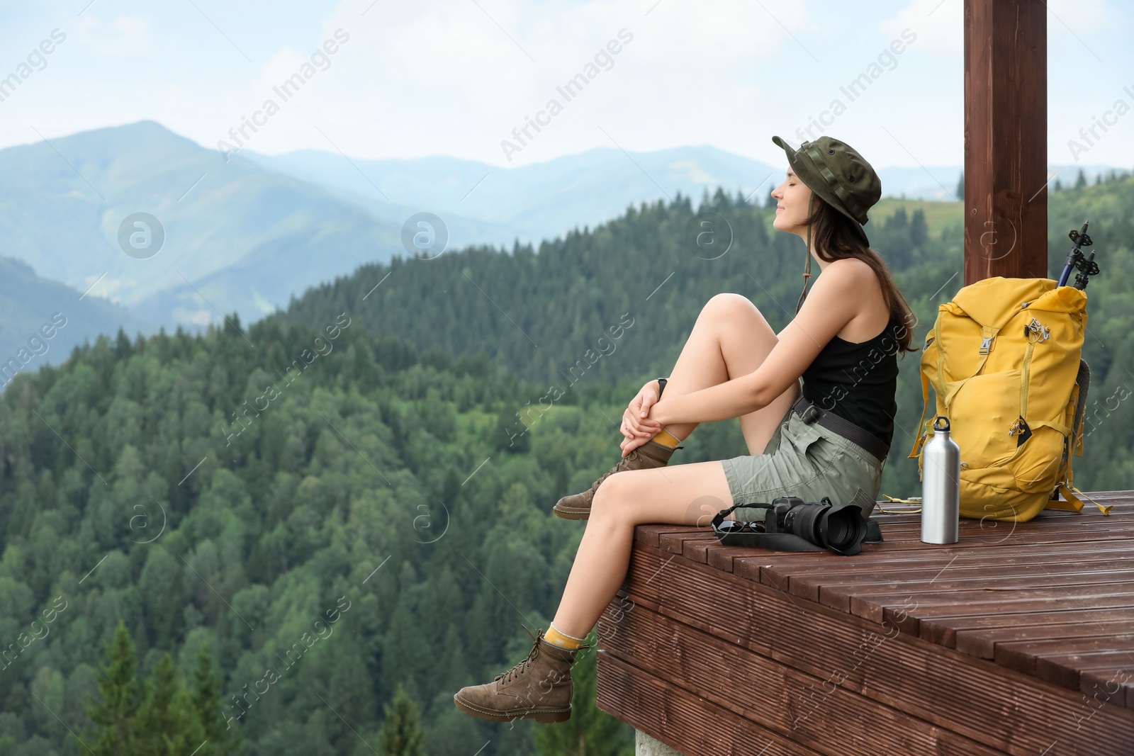 Photo of Young hiker with backpack and camera in mountains, space for text