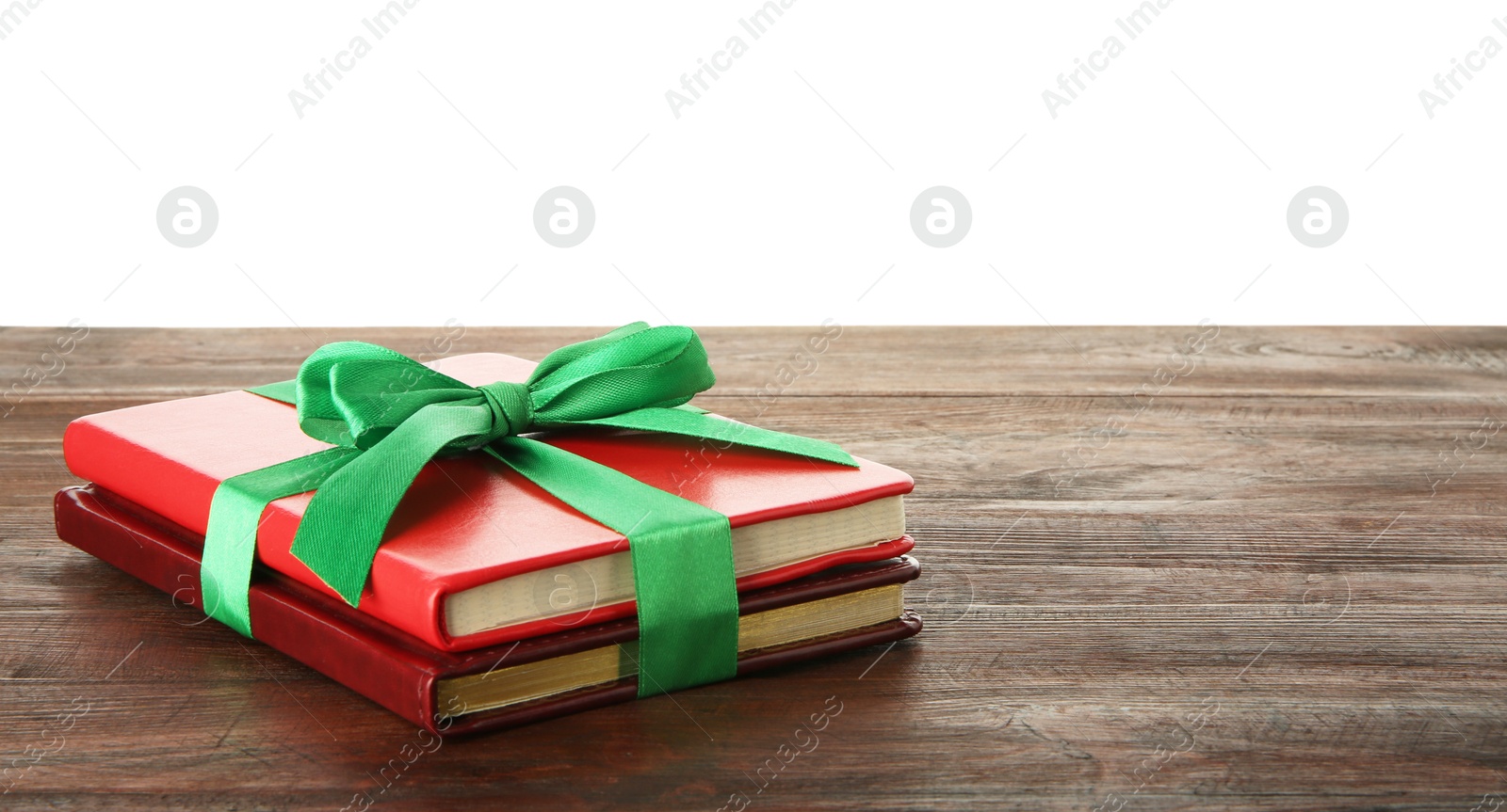 Photo of Books with ribbon as gift on wooden table against white background, space for text