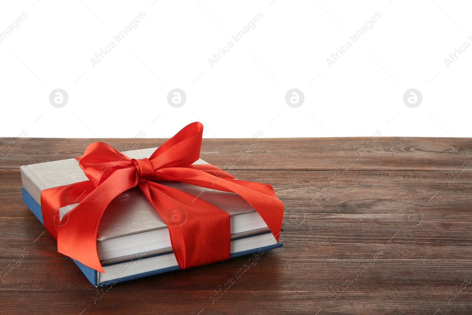 Photo of Books with ribbon as gift on wooden table against white background, space for text