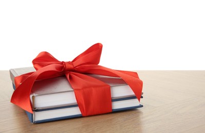 Photo of Books with ribbon as gift on wooden table against white background, space for text