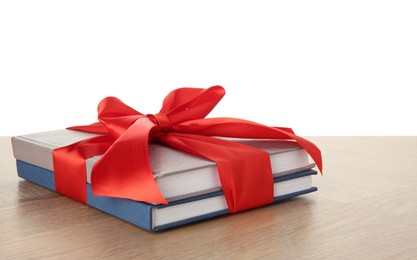 Photo of Books with ribbon as gift on wooden table against white background