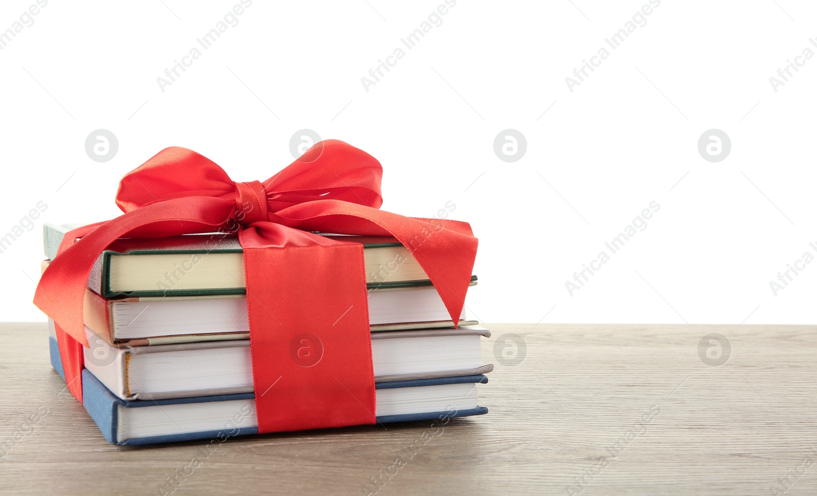 Photo of Stack of books with red ribbon as gift on wooden table against white background, space for text