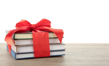 Photo of Stack of books with red ribbon as gift on wooden table against white background, space for text