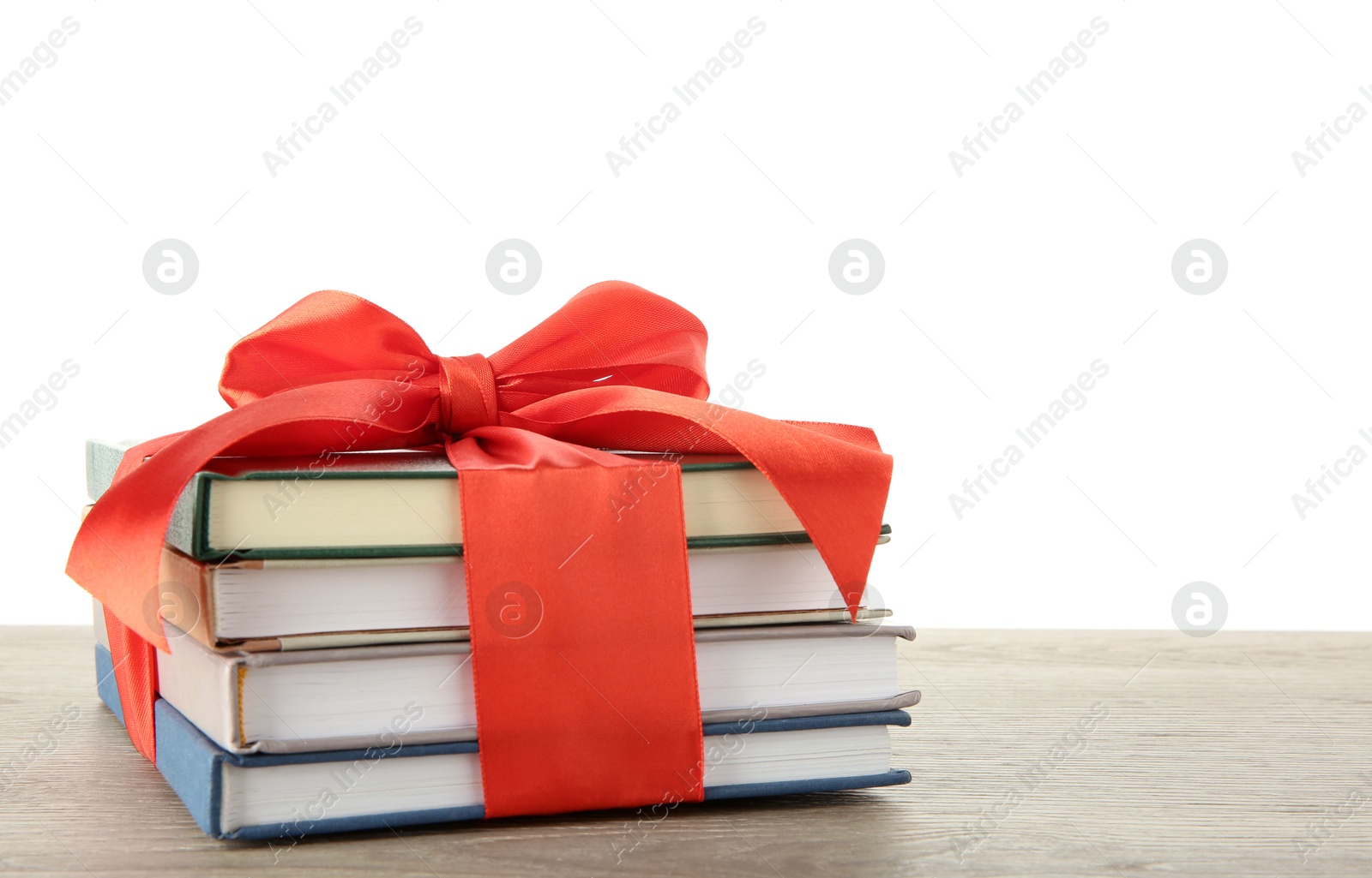 Photo of Stack of books with red ribbon as gift on wooden table against white background, space for text