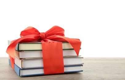 Photo of Stack of books with red ribbon as gift on wooden table against white background, space for text