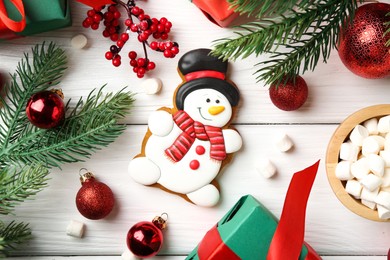 Photo of Delicious cookie in shape of snowman, marshmallows and Christmas decor on white wooden table, flat lay