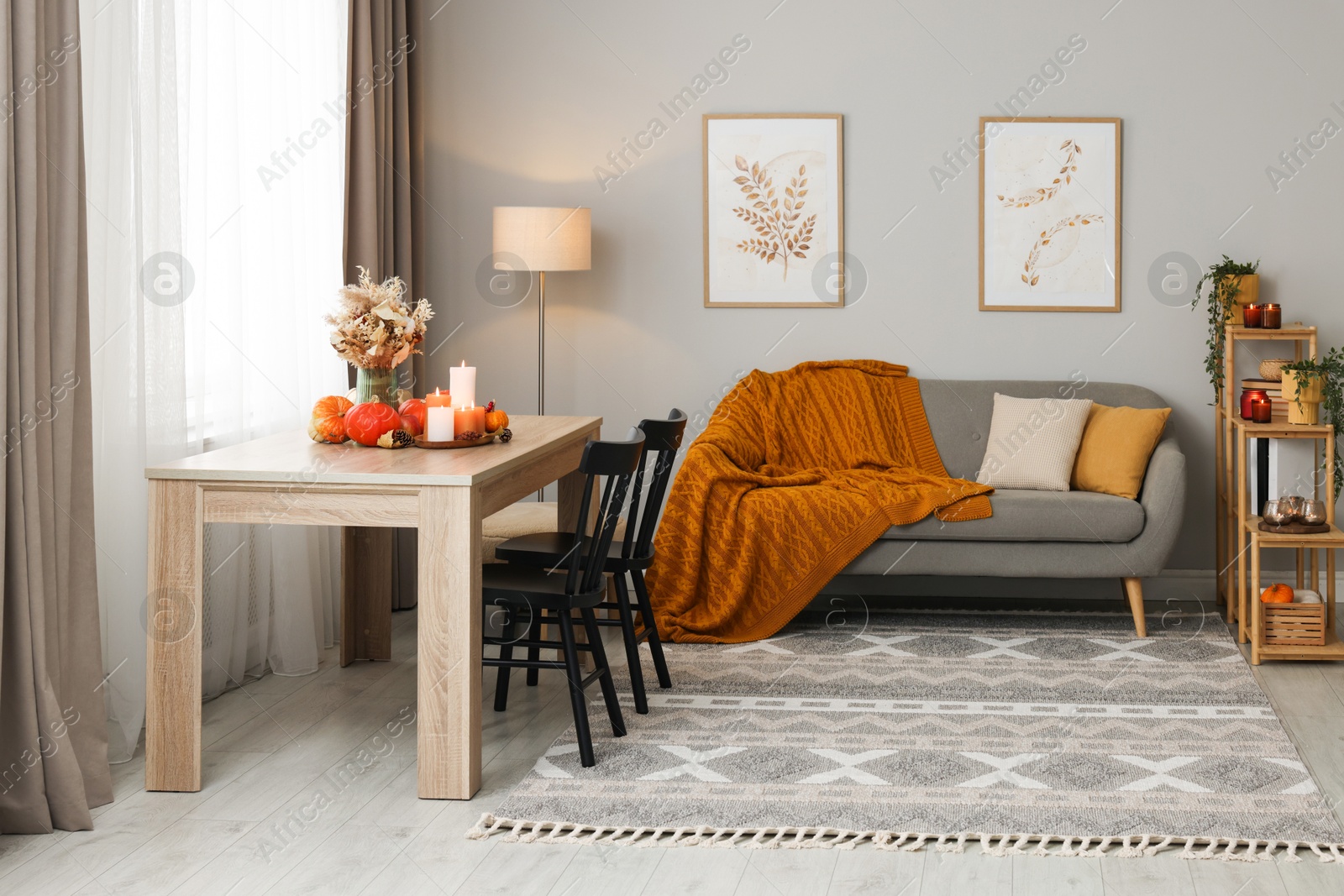 Photo of Burning candles and stylish furniture in cozy room. Autumn atmosphere