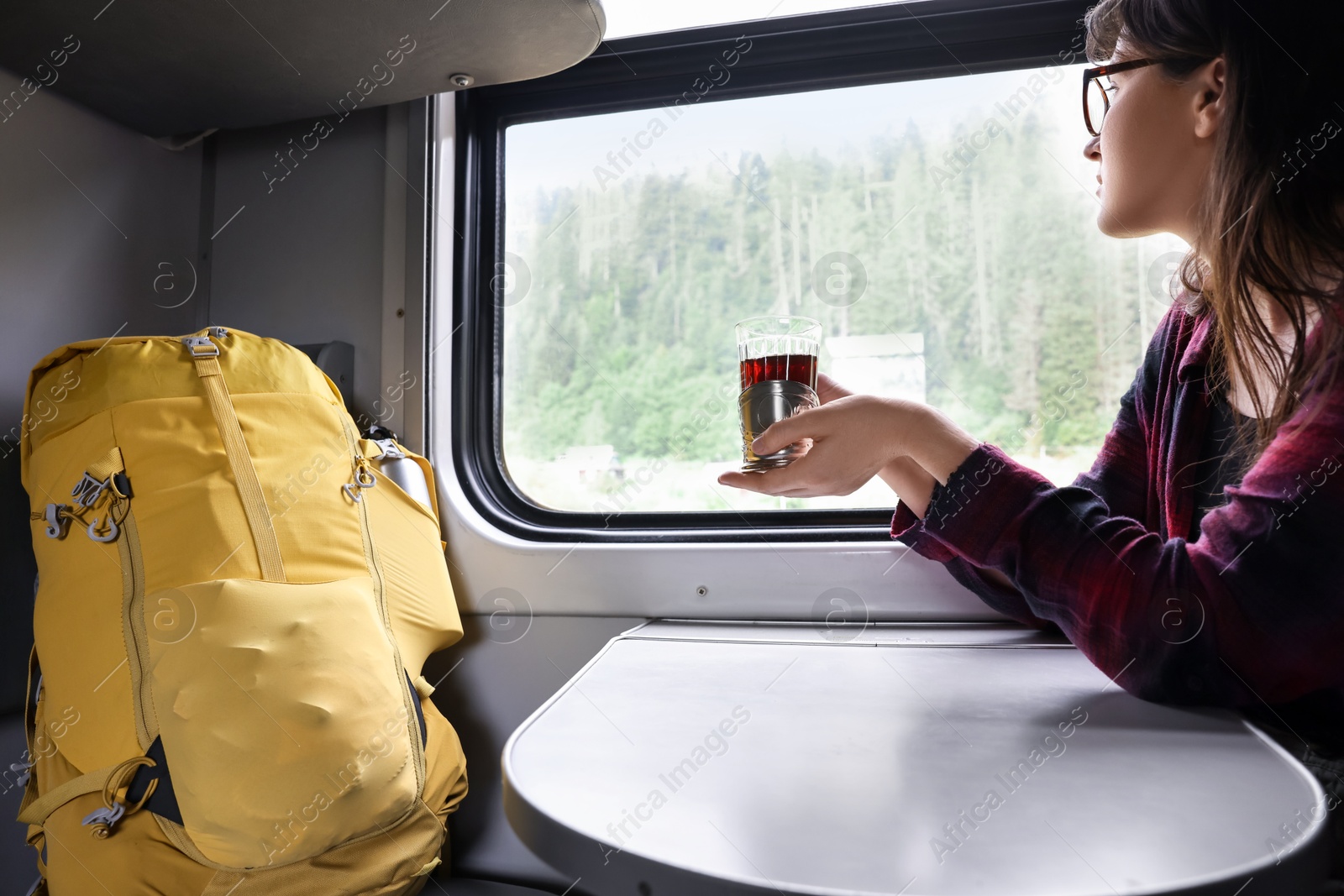 Photo of Young woman with cup of tea at table in train