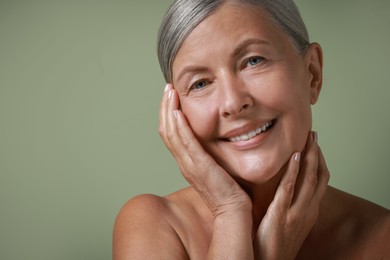 Face massage. Beautiful woman with healthy skin on light green background