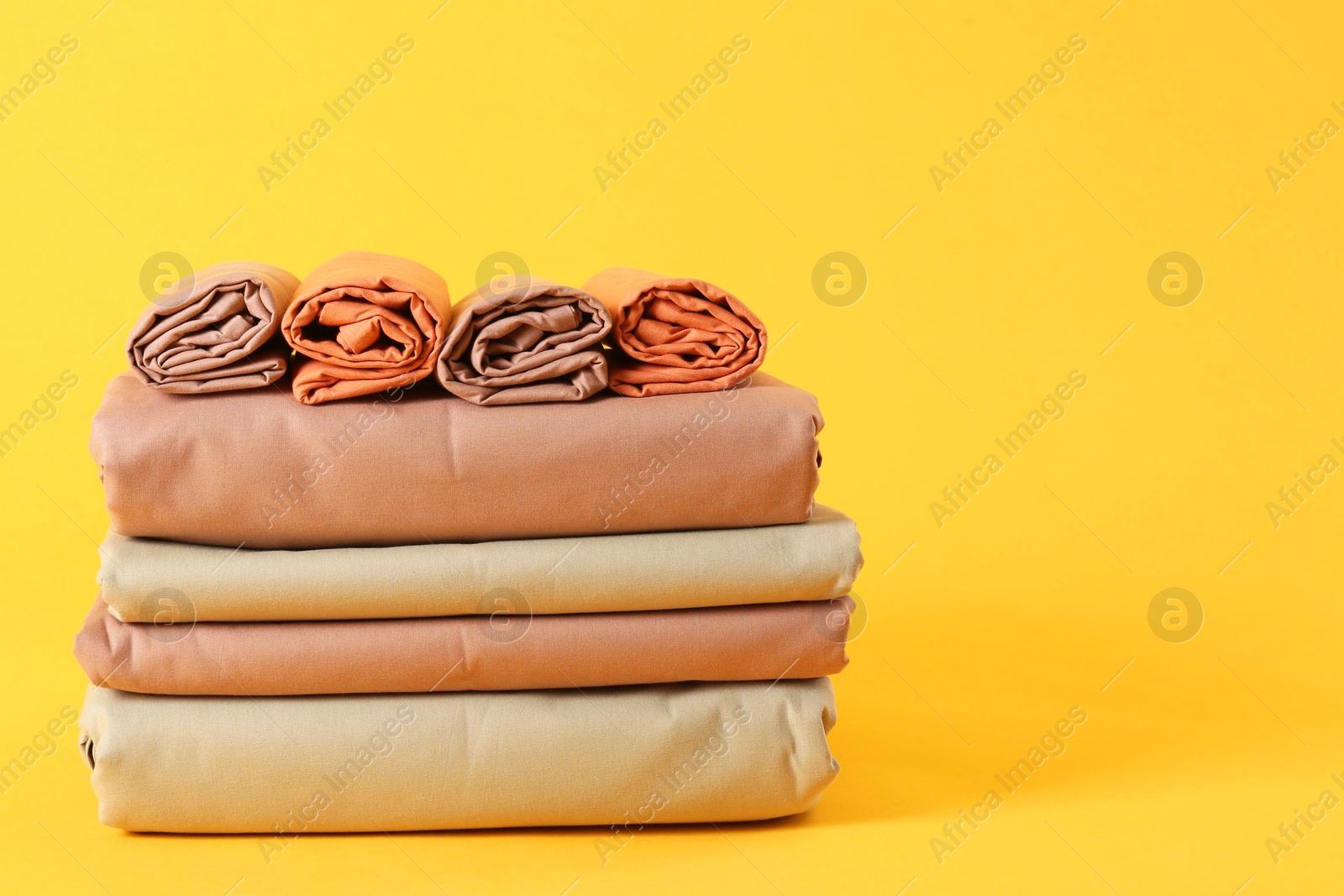 Photo of Stack of clean bed sheets on yellow background