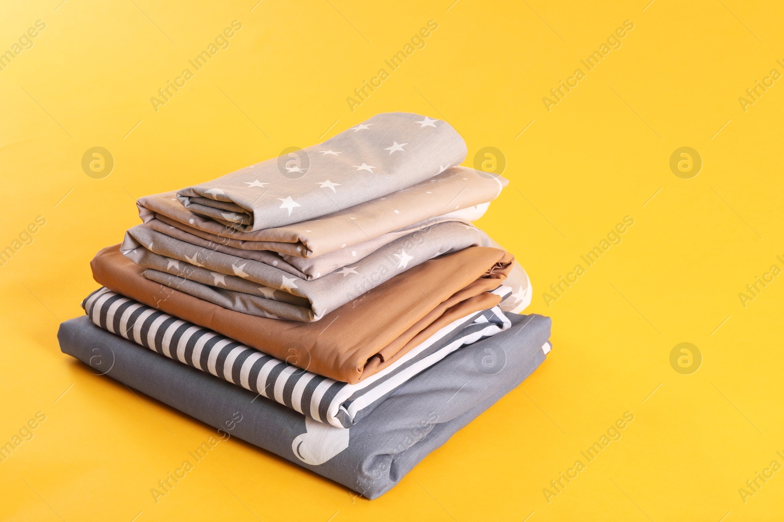 Photo of Stack of clean bed sheets on yellow background