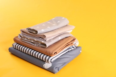 Photo of Stack of clean bed sheets on yellow background