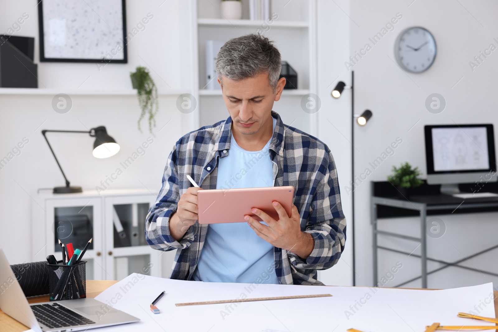 Photo of Architect making digital engineering drawing on tablet at table in office