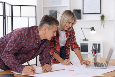 Photo of Architects making engineering drawing at wooden table in office