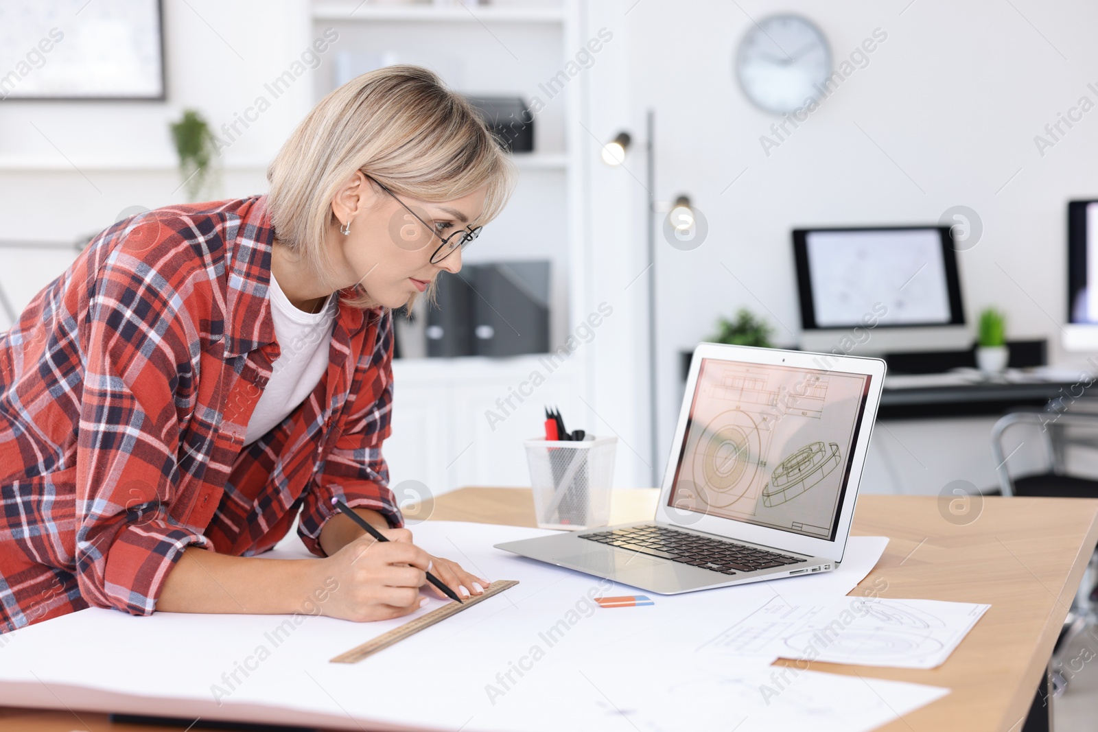 Photo of Architect making engineering drawing at wooden table in office