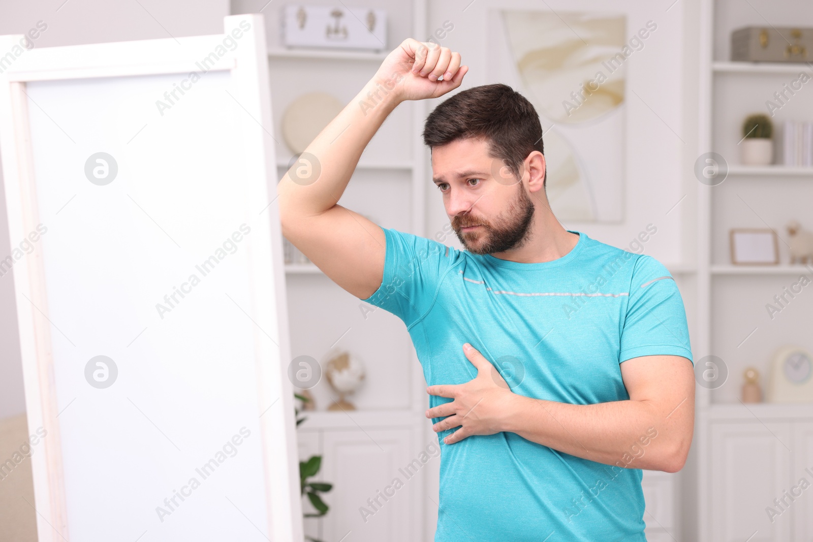 Photo of Emotional man in t-shirt before using deodorant at home