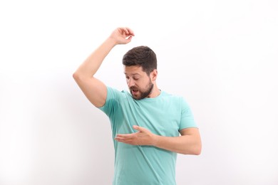 Emotional man in t-shirt before using deodorant on white background