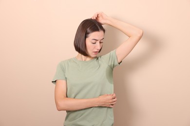 Photo of Emotional woman in t-shirt before using deodorant on beige background