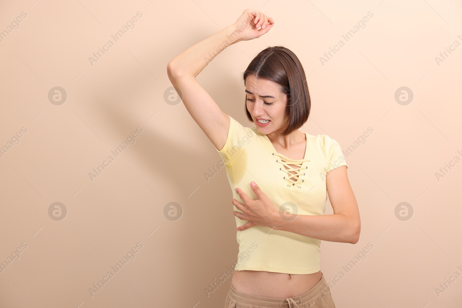 Photo of Emotional woman in t-shirt before using deodorant on beige background. Space for text