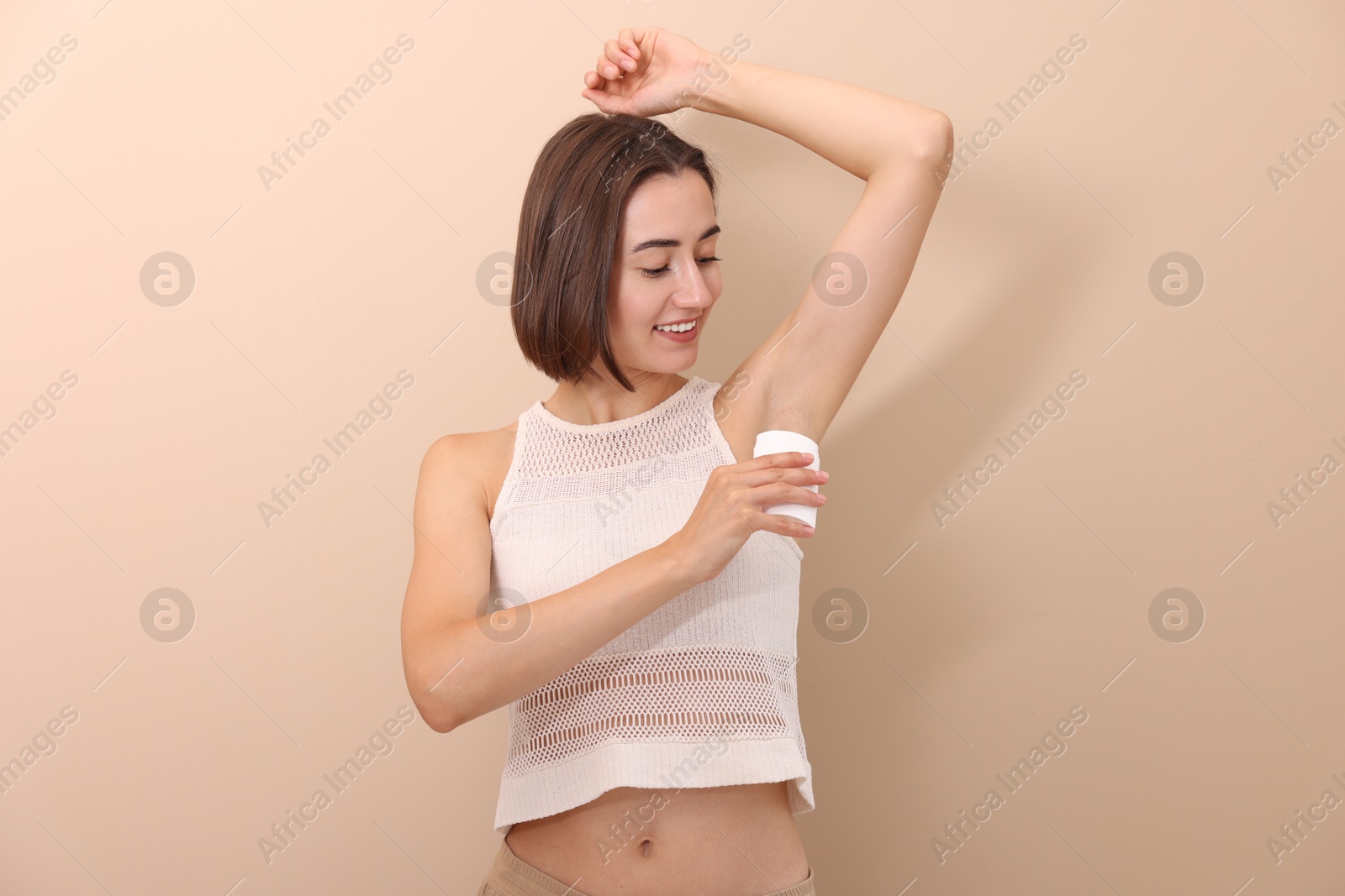 Photo of Smiling woman applying solid deodorant on beige background