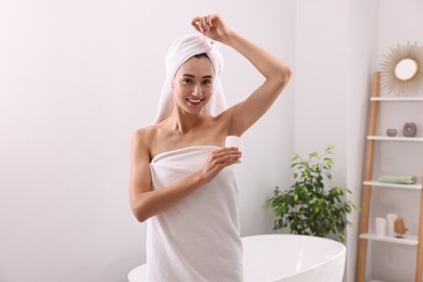 Photo of Smiling woman applying solid deodorant at home