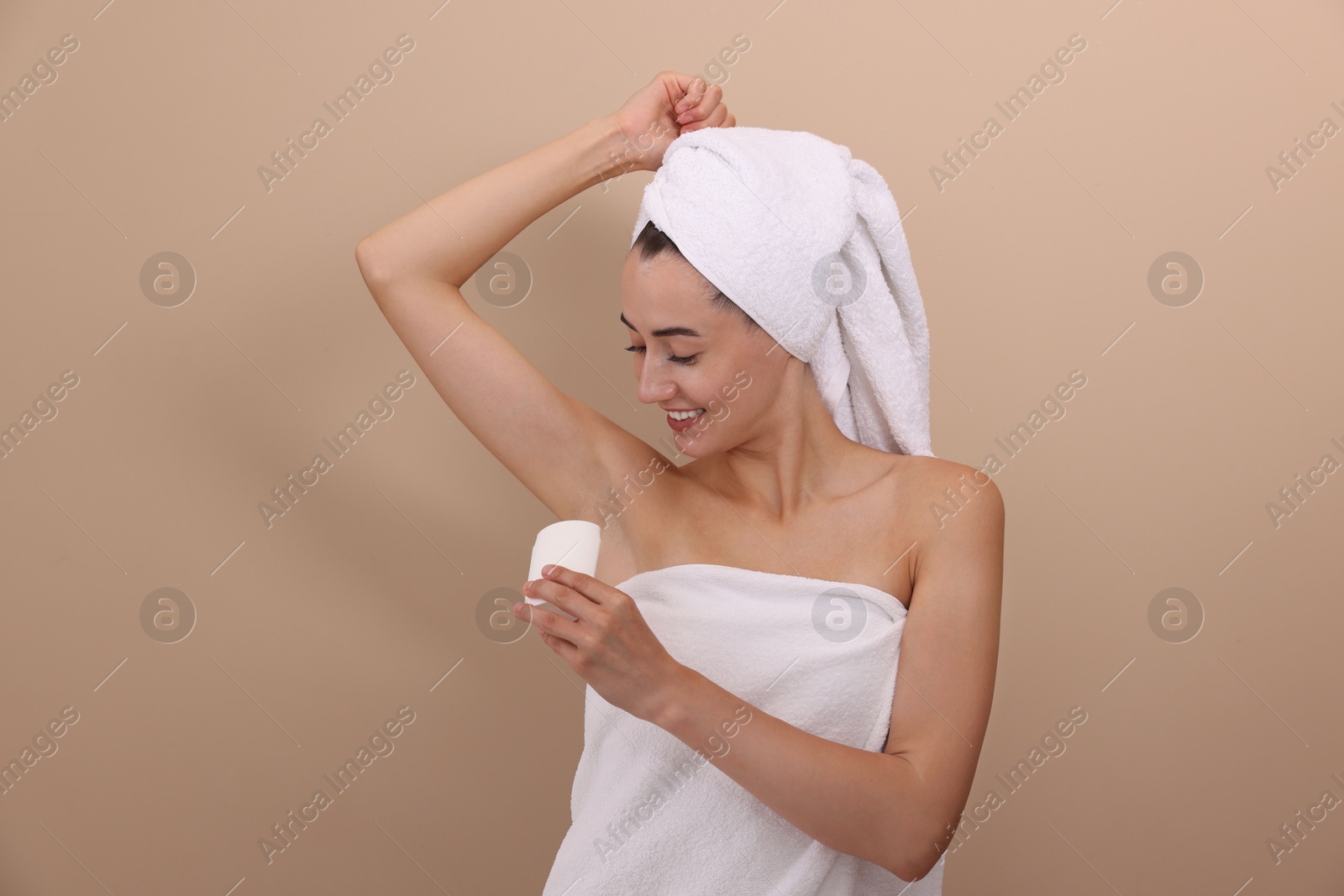 Photo of Smiling woman applying solid deodorant on beige background