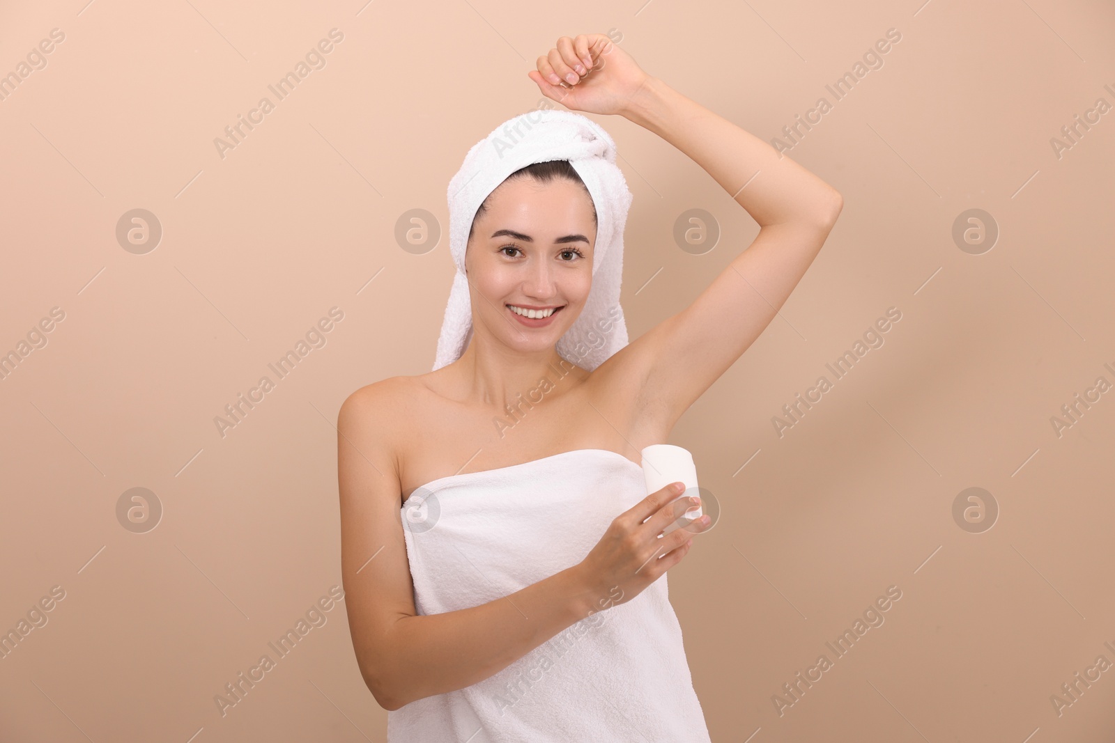 Photo of Smiling woman applying solid deodorant on beige background