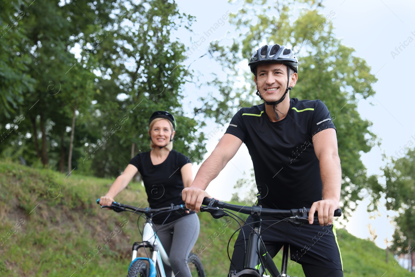 Photo of Happy couple riding bicycles in park, selective focus