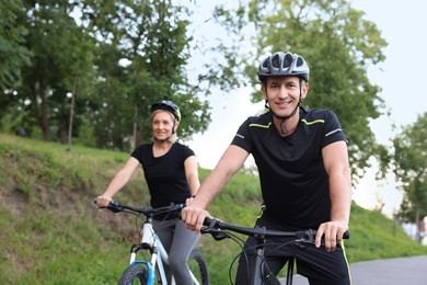 Photo of Happy couple riding bicycles in park, selective focus