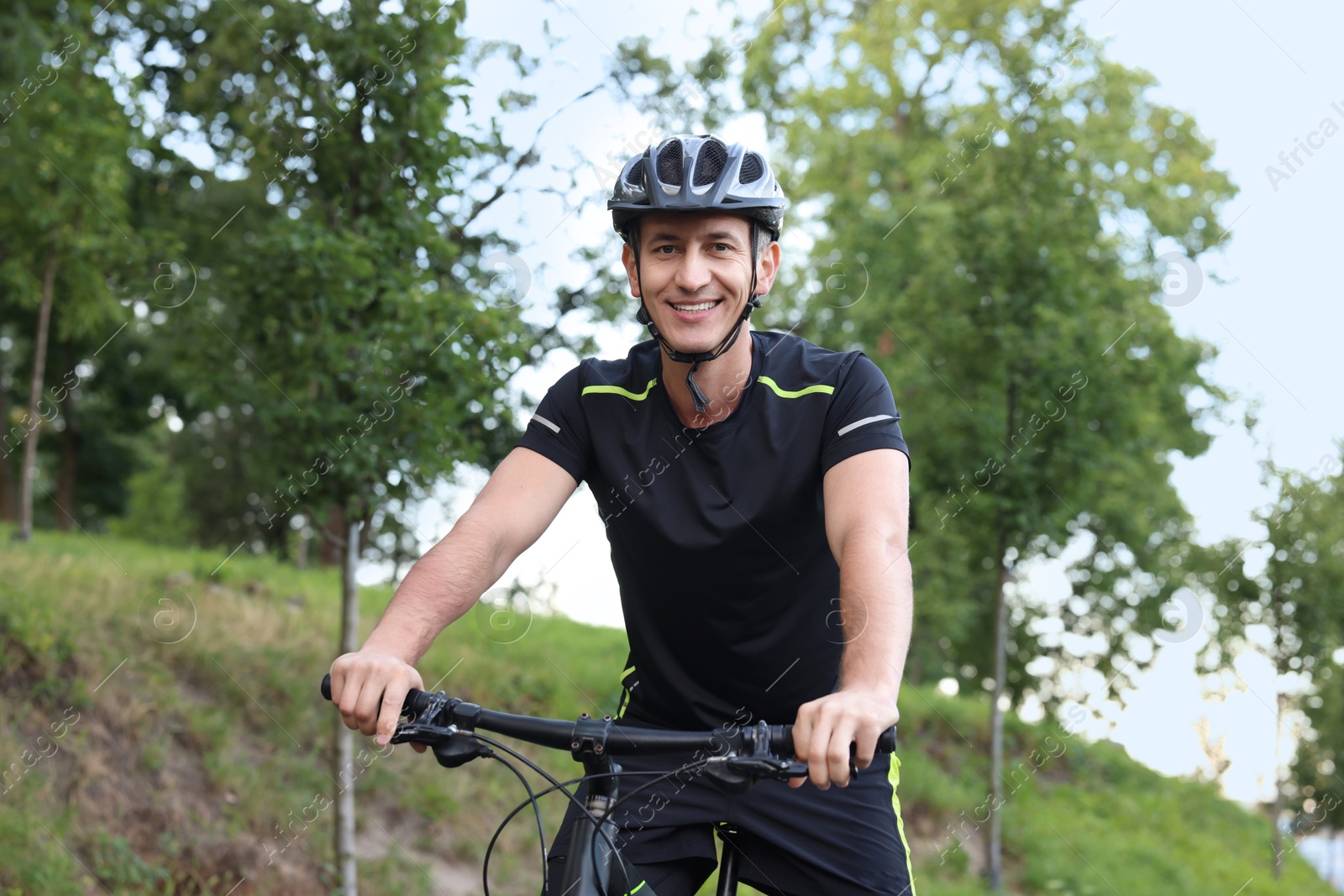 Photo of Happy man riding bicycle in park. Healthy lifestyle